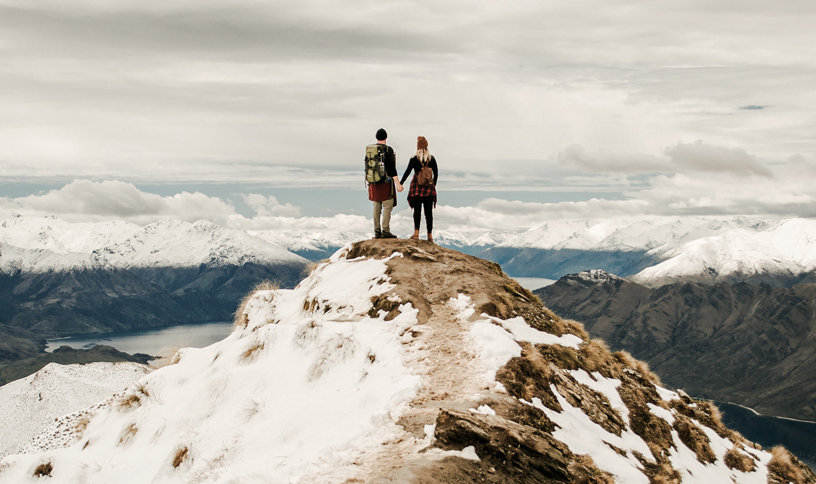 Paar blickt von verschneitem Gipfel in die Ferne