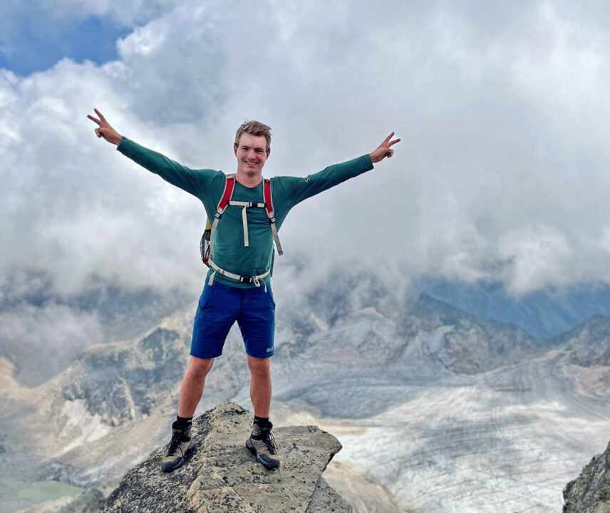 Emil steht auf einer Klippe vor einem Gletscher. Am Himmel sind große, nierige Quellwolken.