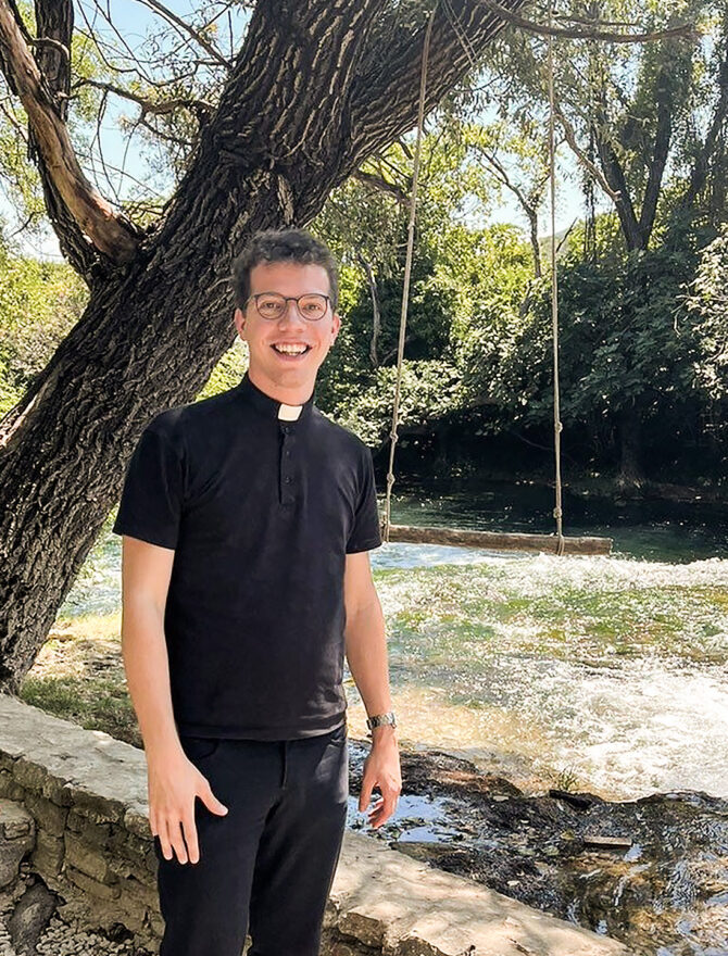 Junger Priester vor einem Baum