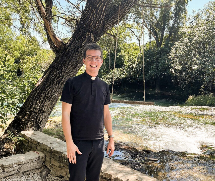 Junger Priester vor einem Baum