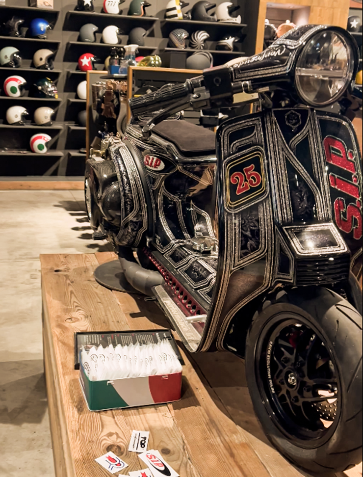 Ausgestellter Motorroller vor einer Ladenwand mit Rollerhelmen